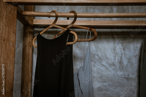 Boho chic Little black dress hanging on a  clothing rack, rappan wooden hangers. Boho chic style. Fashion blogging concept, neutral colors. Loft bedroom interior design wooden clothing rack © Iuliia