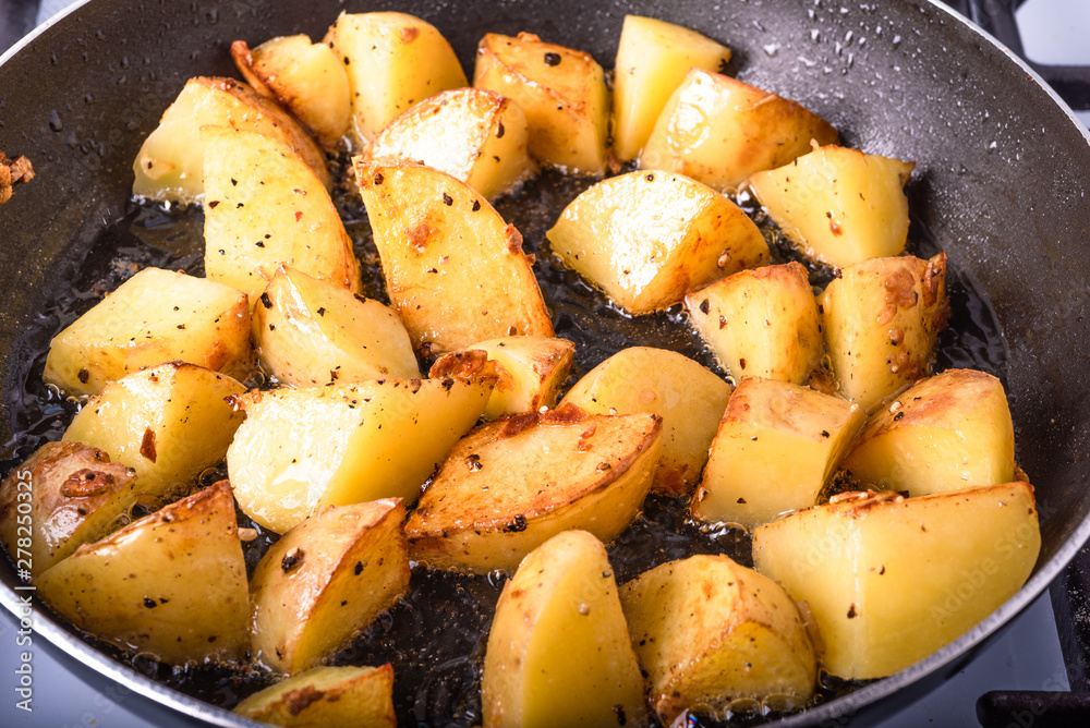 Cooking a rustic breakfast - large pieces of potatoes are fried in a pan Cooking a rustic breakfast - large pieces of potatoes are fried in a pan