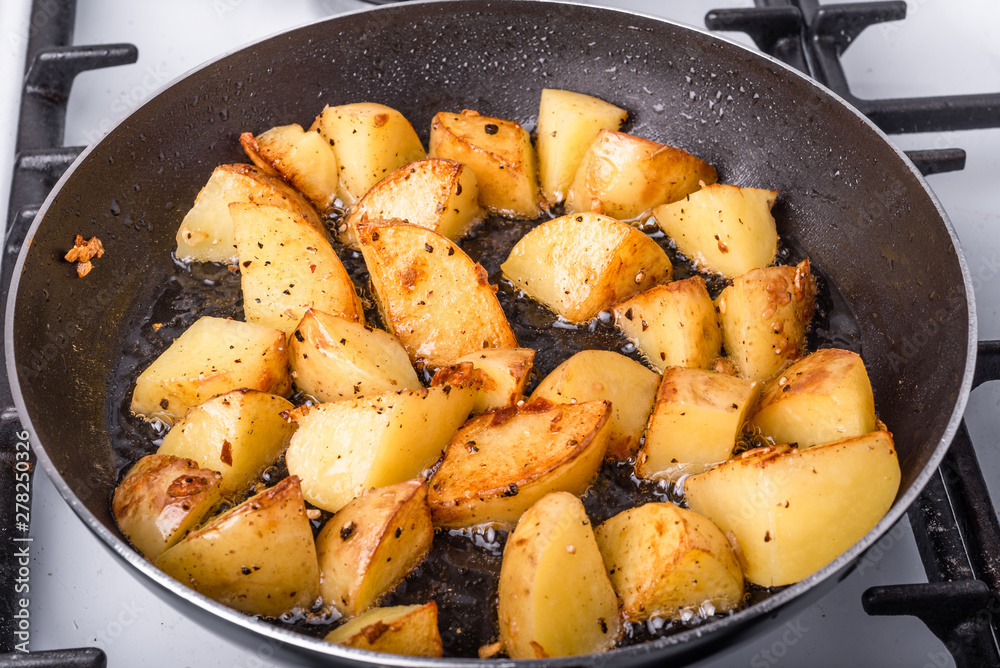 Cooking a rustic breakfast - large pieces of potatoes are fried in a pan Cooking a rustic breakfast - large pieces of potatoes are fried in a pan