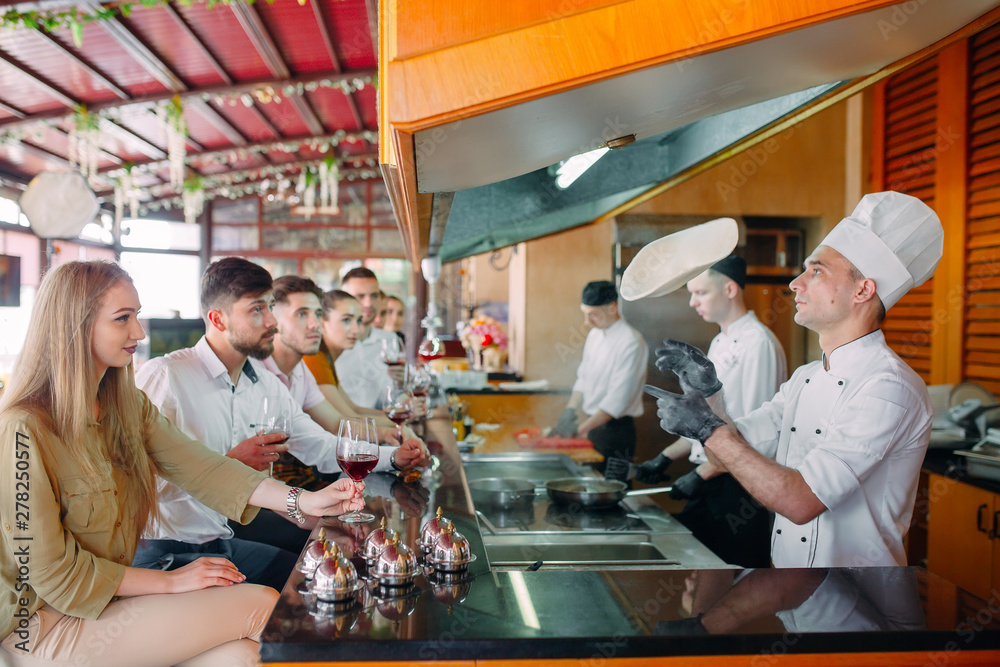 The chef prepares food in front of the visitors in the restaurant The chef prepares food in front of the visitors in the restaurant