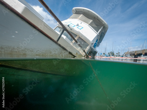 Close-Up Underwater and Above Water Split Shot of a Listing, Half-Sunken Abandoned Boat photo