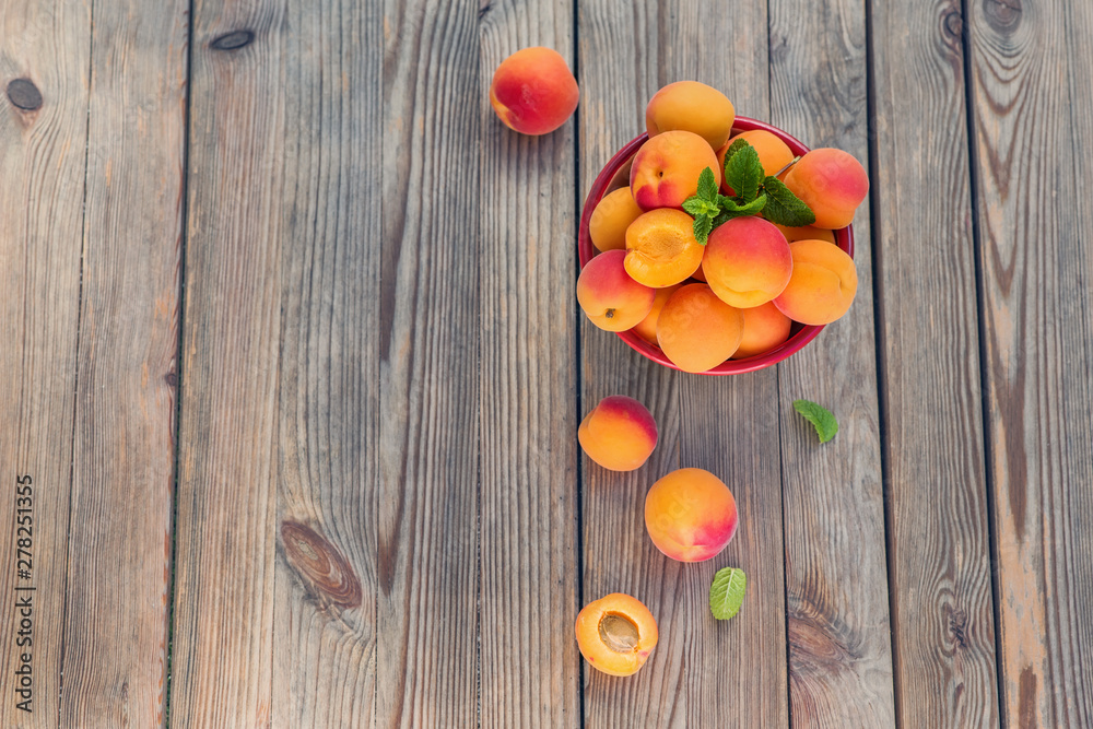 Ripe apricots in a bowl on wooden rustic background copy space - obrazy, fototapety, plakaty 