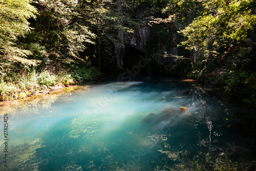 Beautiful blue color of the source of cold water deep in the cave of beautiful forest and untouched nature with sunrises. River deep in mountain forest. Nature composition. Water spring in forest.