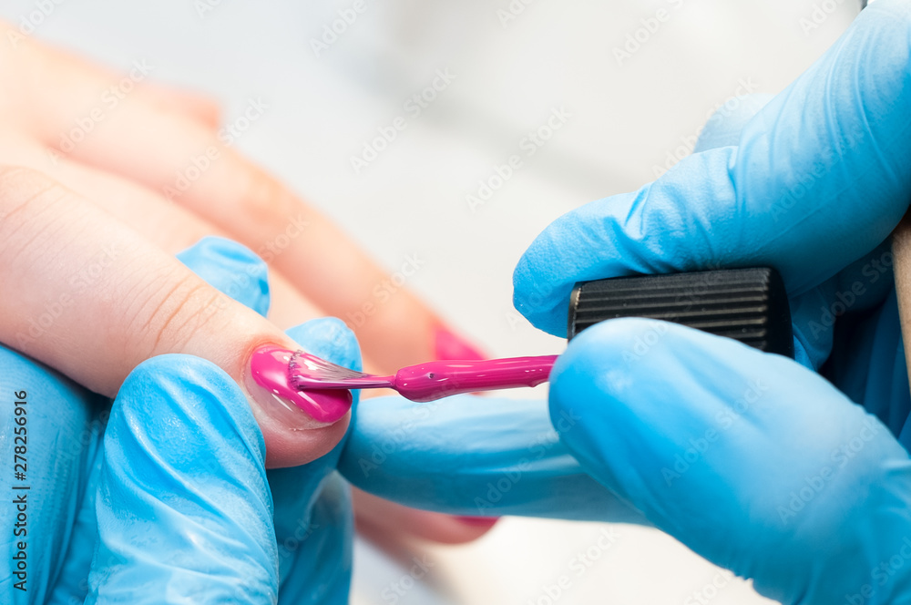 Manicure nail paint pink color. Nail care. Closeup of beautiful woman hands getting manicure in spa salon. Female manicurist cleaning cuticle with professional manicure. Cosmetic procedure. Manicure nail paint pink color. Nail care. Closeup of beautiful woman hands getting manicure in spa salon. Female manicurist cleaning cuticle with professional manicure. Cosmetic procedure.