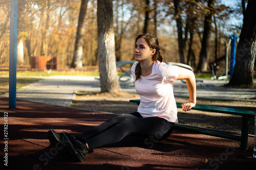 Photos Beautiful woman doing sport on outdoor park during fall and sunset - triceps exe