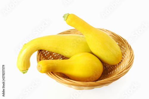 whole fresh yellow crookneck squash in basket on white background photo