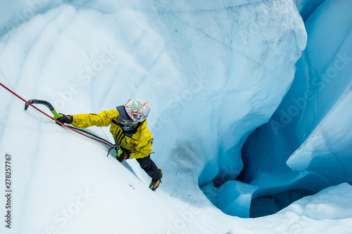 Ice climber ascending out of a moulin on the Matanuska Glacier in Alaska.