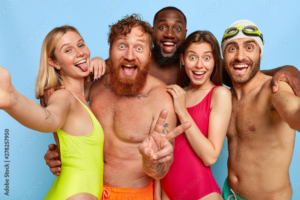 Multiracial group of young friends make selfie photo, show tongue and peace gesture, spend weekend at beach during summer, have funny outdoor activities. Friendship, leisure, vacation concept - obrazy, fototapety, plakaty 