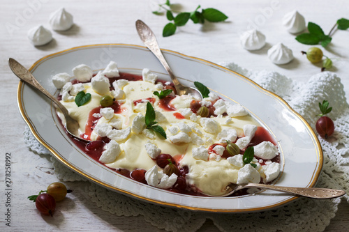 Eton mess, traditional English dessert with gooseberry, whipped cream and meringue on a light background. Rustic style. photo