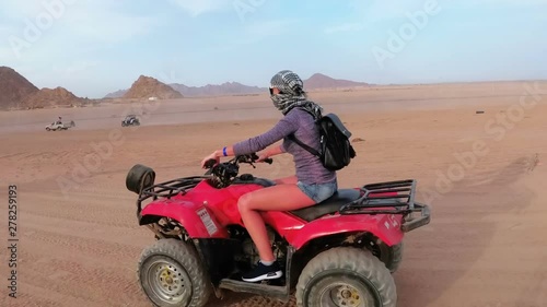 Woman is Riding a Quad Bike in the Desert of Egypt. Dynamic view in motion. photo