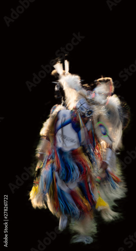 Fotografie Motion blurred image of a Native Americans powwow dance on black background