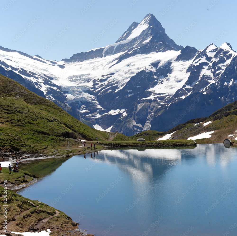Great view of Bernese mountains above Bachalpsee lake. Dramatic and picturesque scene. Popular tourist attraction with people enjoying the day.