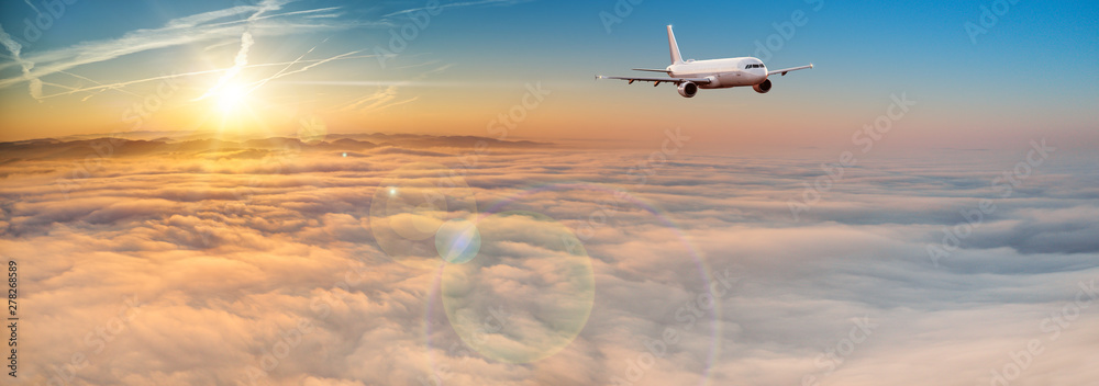 Commercial airplane jetliner flying above dramatic clouds in beautiful sunset light. Travel concept.