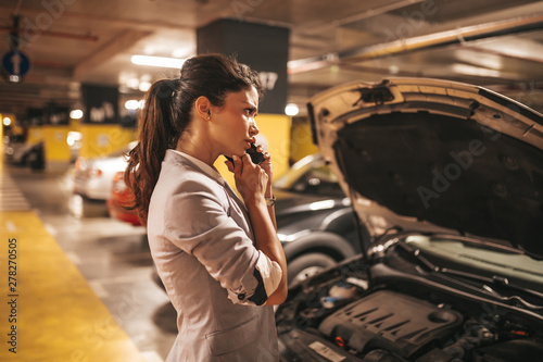 Frustrated and distressed woman has a car failure at public place in underground garage. photo