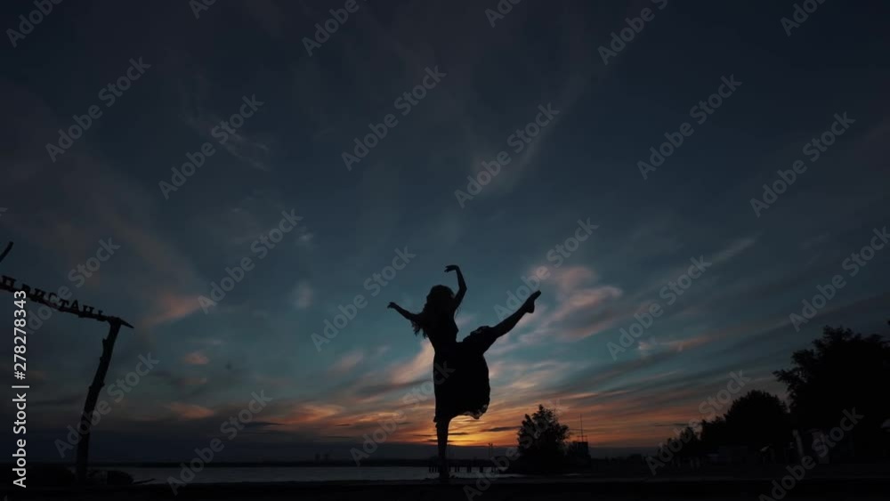 silhouette of a ballerina against the sunset sky. the girl beautifully dances standing on tiptoes.