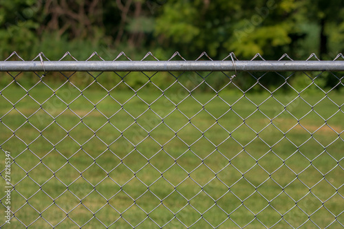 Chain link fence with grass and trees in background