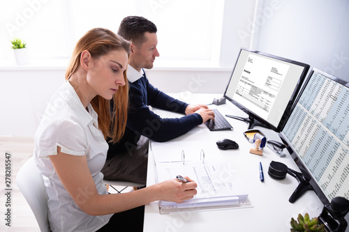 Auditors Working On Computer With Invoice photo