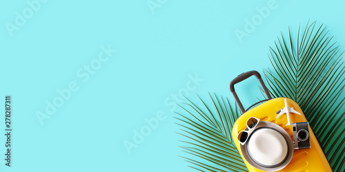 Flat lay yellow suitcase with traveler accessories and tropical palm leaves on blue background. travel concept. 3d rendering