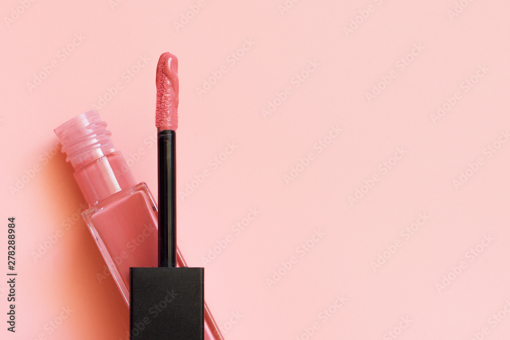 Liquid lipstick and applicator on coral pink color background. Open tube of lip gloss and wand brush with makeup product on pastel coral surface. Top view, flat lay, copy space - obrazy, fototapety, plakaty 