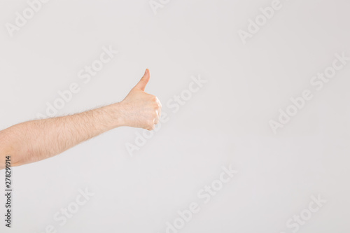 Closeup of male hand showing thumbs up sign against white background with copy space