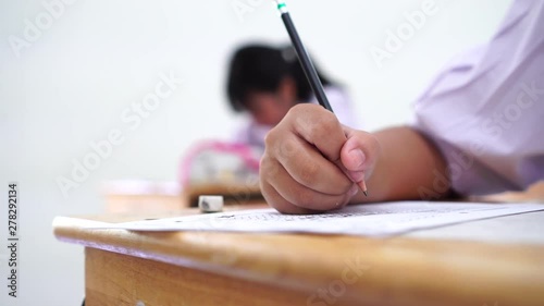 English exams test student in school, university students holding pencil for testing exam writing answer sheet or exercise for taking in assessment paper on table classroom. Education study Concept