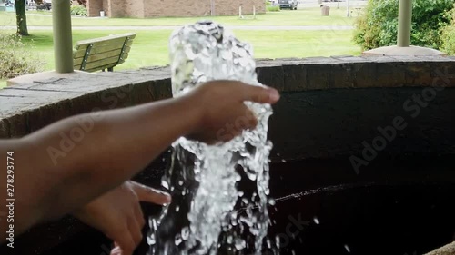Child plays with bubbling artesian well spring in public mineral springs gazebo