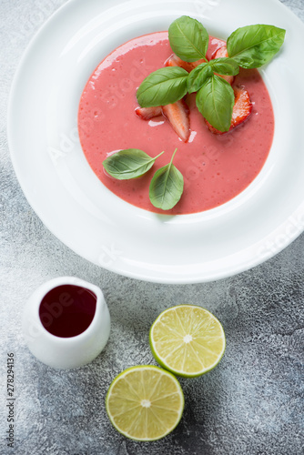 Above view of a white plate with strawberry cream-soup, vertical shot