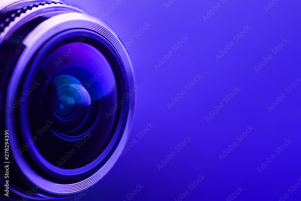 Camera lens with purple backlight. Side view of the lens of camera on purple background. Purple camera Lens close Up. Camera lens with purple backlight. Side view of the lens of camera on purple background. Purple camera Lens close Up.