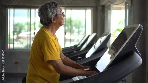 asian Senior man walking exercise on treadmill workout in fitness gym . sport , trainnig , retired , older , mature, elderly photo