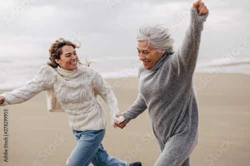 Active senior woman and her daughter enjoying on the beach in winter. photo