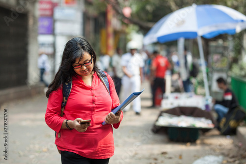 College student standing in a busy street in a city and browsing internet