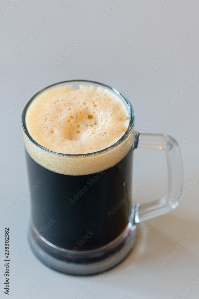 Glass of dark beer on a gray background. vertical photo Glass of dark beer on a gray background. vertical photo