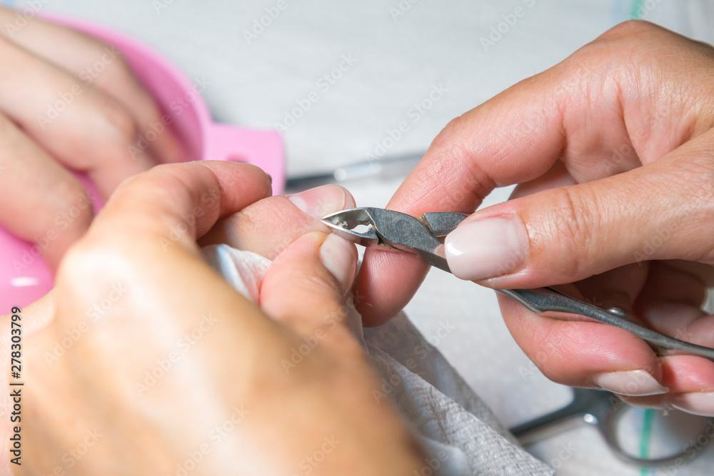 Woman hands receiving manicure and nail care procedure. Close up concept. Manicurist pushing cuticles on female's nails. female nail manicure processing