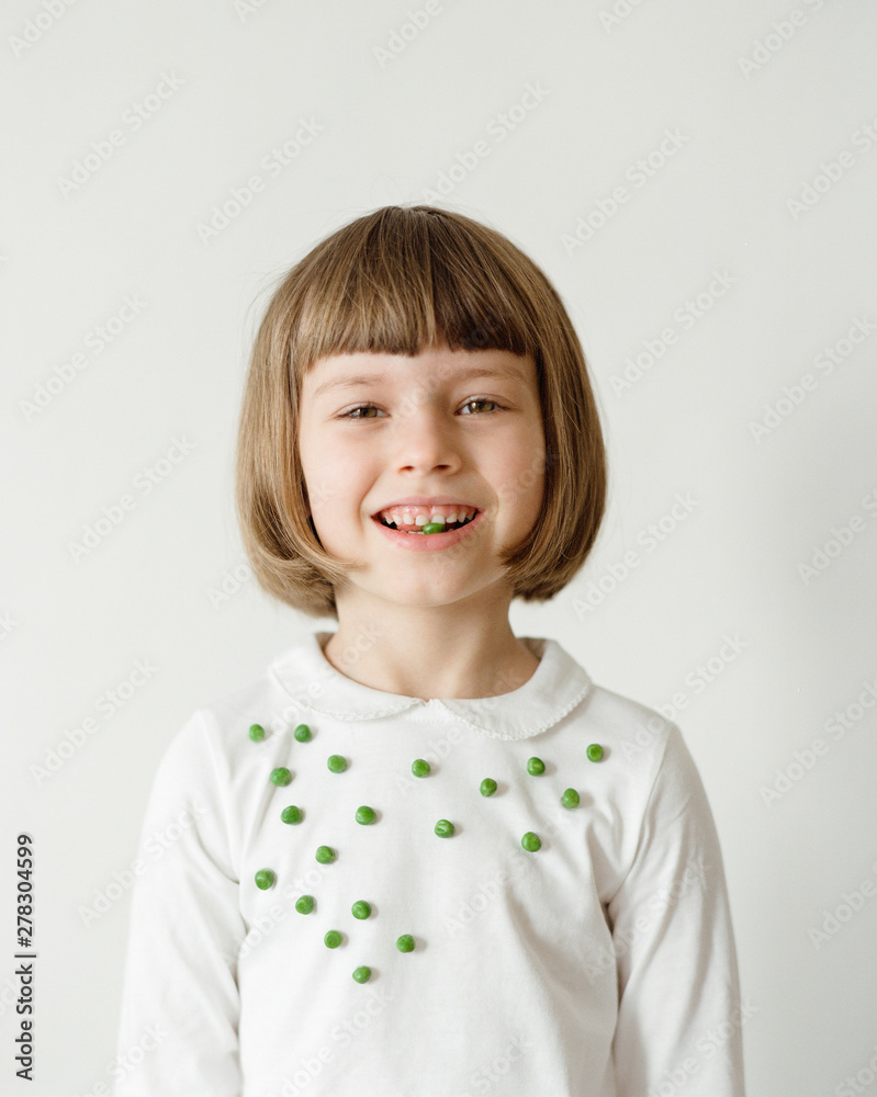 Cheerful girl with peas in mouth