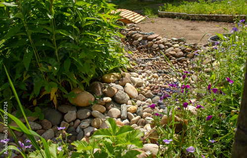 Dry creek in the garden of stones. grass and flowers grow along the bank of the brook. photo