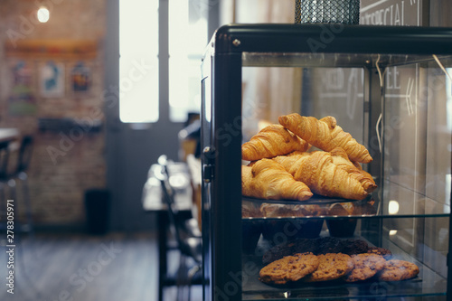 Close up of a display case with croissants and cookies in a coffee shop