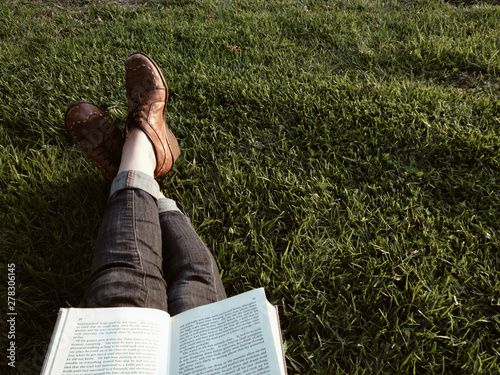 legs stretched out reading book on grass