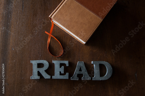 leather book with metal letter spelling out the word READ underneath