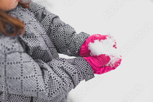 Smiling girl with bright pink hat plays in snow