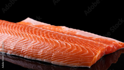 Raw salmon filet isolated on dark background. Uncooked salmon fillet