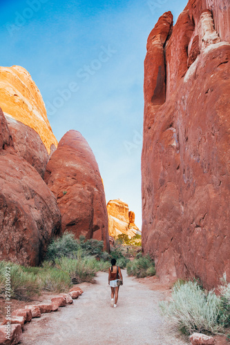 A girl walks under an arch of rust red rock in the Wesern American Desert photo