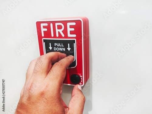The male hand is pushing the fire alarm.  