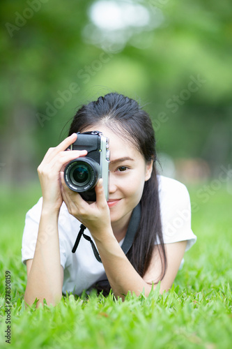 woman or girl photographer taking picture with retro camera lie down on grass, lifestyle and relaxing concept