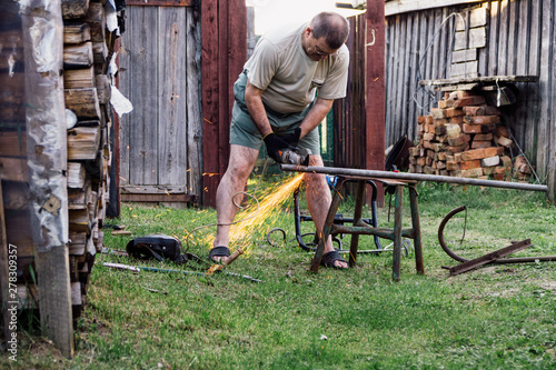 Mature man working with grinder saw outdoors.