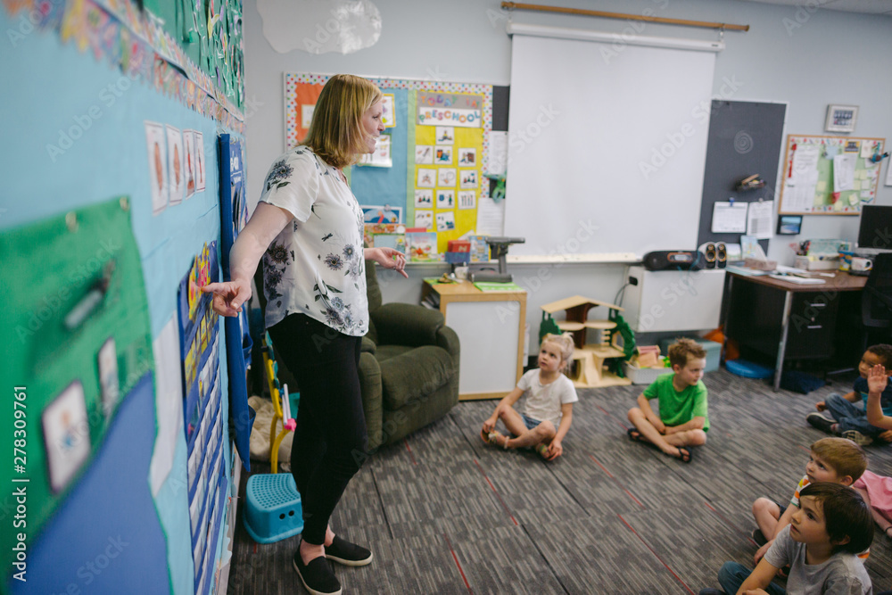 Teacher interacting with students sitting on carpet in classroom