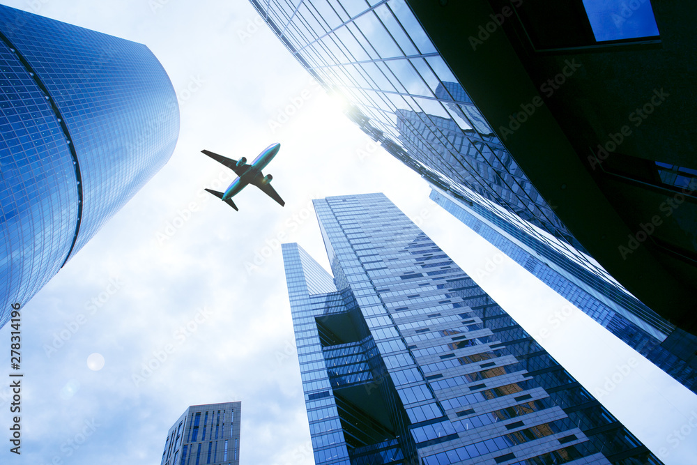 Airplane flying over business skyscrapers. Business and transport, transportation, travel concept. Business trip background.
