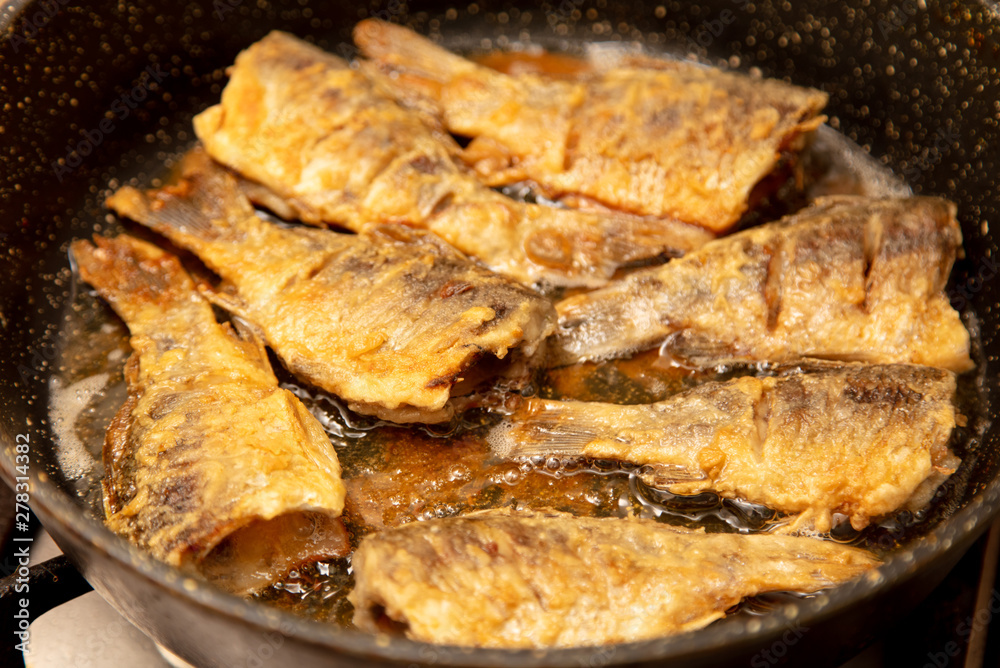 Fried fish in a pan in the kitchen