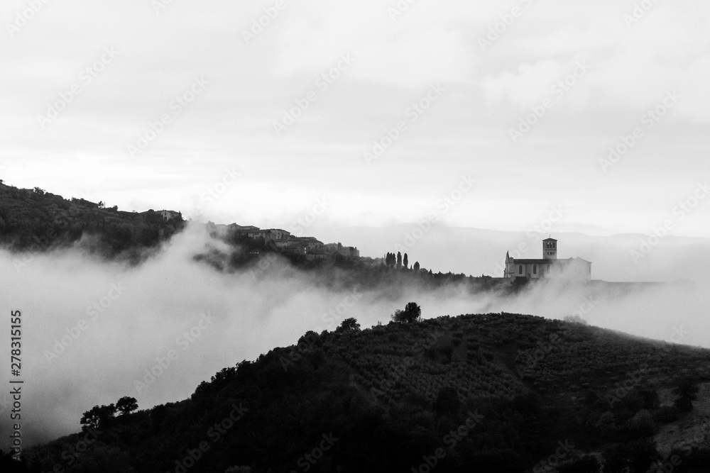 A view of St Francis church in Assisi (Umbria, Italy) veiled by fog, with an hill in the foreground