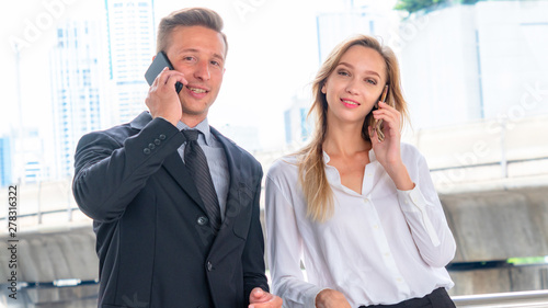 man and woman talking with smart phone at outdoor with transport sky train passing in background. Concept of business meeting life. photo