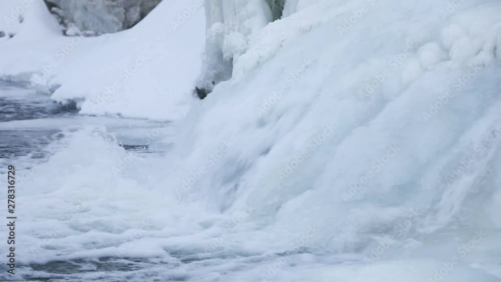 Pan right, waterfall cascades through ice Pan right, waterfall cascades through ice